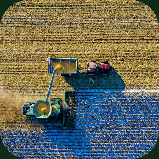 Vedere de sus a unei combine care descarcă recolta într-o remorcă, pe un teren agricol